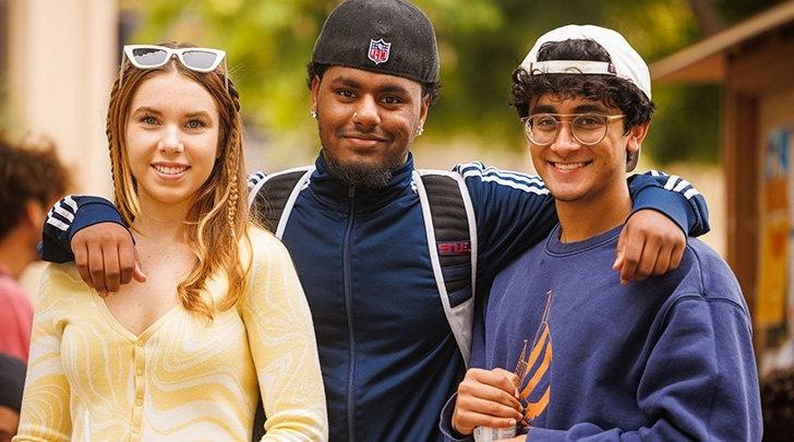 three students smile at the camera in scott courtyard